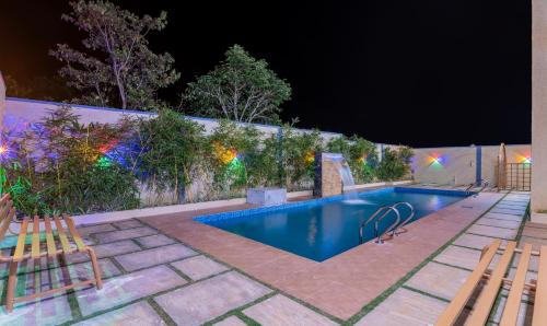a swimming pool at night with two chairs and a fence at Itsy Hotels Kurinji Stay Inn in Yelagiri