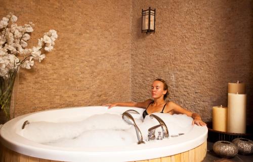 kobieta siedząca w wannie w łazience w obiekcie Limak Atlantis Deluxe Hotel Belek w mieście Belek