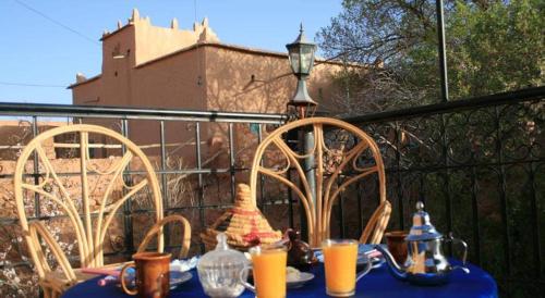 a blue table with chairs and a lamp on a balcony at ECOLODGE MISS ROSE CHEZ LA FAMILLE in Boumalne