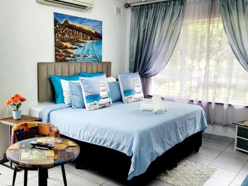 a bedroom with a bed with blue pillows and a table at 7 on Mendoza in Durban