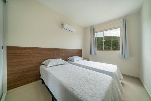 a bedroom with two beds and a window at Aluguel Apartamento 3 Quartos s 1 Suite Bombas in Bombas