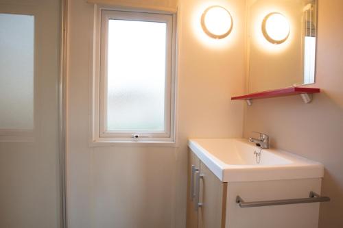 baño con lavabo y ventana en CAMPING LA CLE DE SAONE en Crêches-sur-Saône