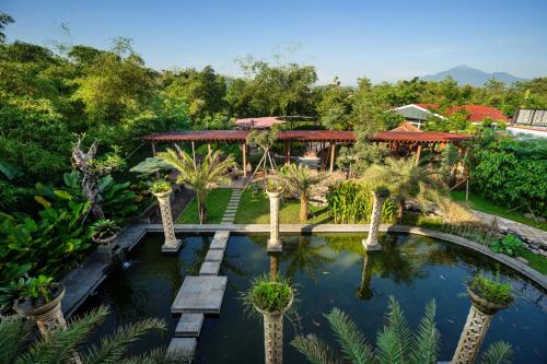 un jardín con un estanque con palmeras y un edificio en NIWA CANTING en Brumbung