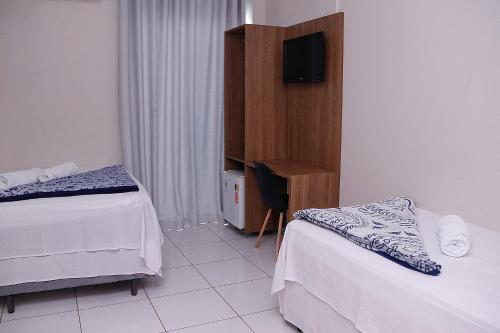 a hotel room with two beds and a television at Palace Hotel in Bom Jesus da Lapa