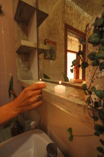 a person lighting candles in a bathroom with a toilet at Casa Örüm in Florianópolis