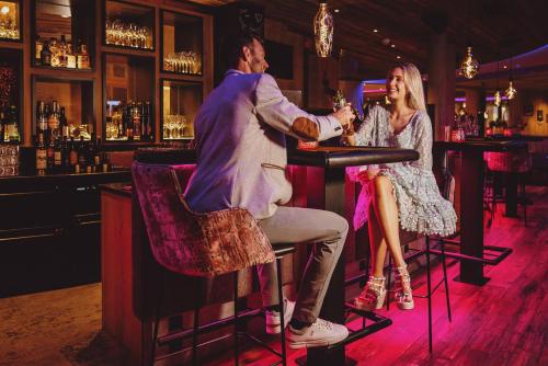a man and a woman sitting at a bar at Superior Sport und Familienresort Alpenblick in Zell am See