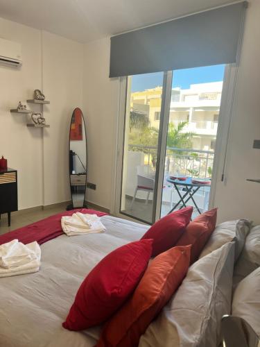 sypialnia z dużym łóżkiem z czerwonymi poduszkami w obiekcie Oceania bay village Pyla w Larnace