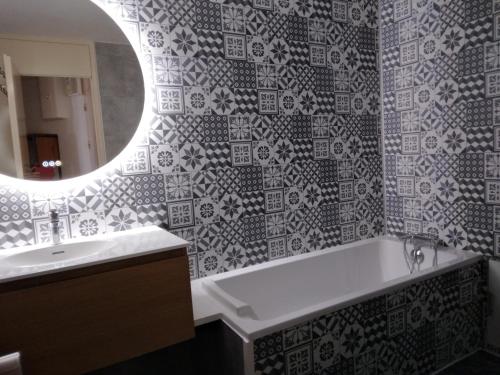 une salle de bain avec une baignoire, un lavabo et un miroir dans l'établissement travelski home classic - Résidence Les Glaciers by Travelski, à La Plagne