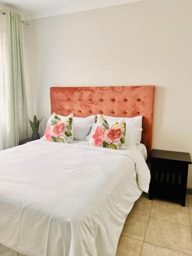 Un dormitorio con una cama blanca con flores rosas. en Makarios en Pretoria