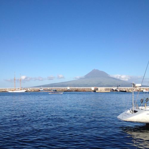 a boat in the water with a mountain in the background at Baía das Caldeirinhas in Horta
