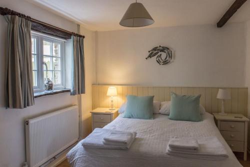Un dormitorio con una cama con almohadas azules y una ventana en The Linhay en Hartland