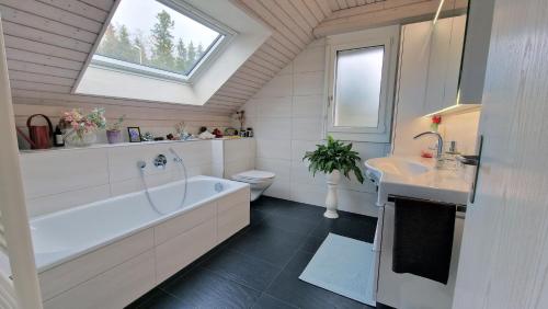 a bathroom with a tub and a toilet and a sink at MENBERGS HARMONY HOMESTAY in Hildisrieden