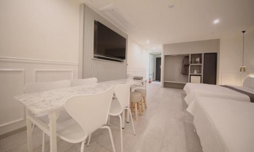 a white dining room with a white table and chairs at Yeongdo Grandbern Hotel in Busan