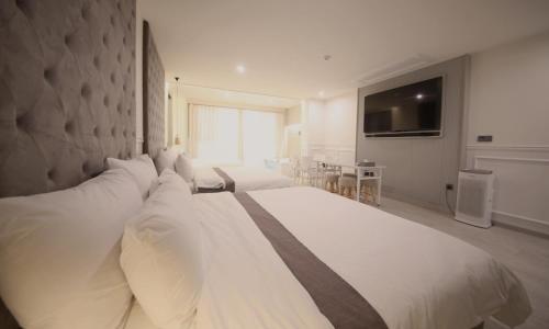 a large white bed with pillows in a bedroom at Yeongdo Grandbern Hotel in Busan