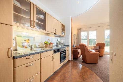 a kitchen with wooden cabinets and a living room at Ferienwohnung Margaretha, App 18 in Ostseebad Sellin