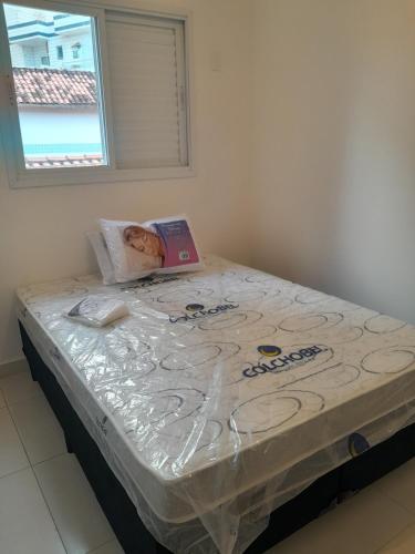a bed covered in plastic with a book on it at CASA NA PRAIA GRANDE pé na areia in Praia Grande