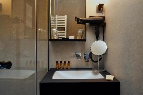 a bathroom with a shower and a sink with a mirror at The Hotel Ljubljana in Ljubljana