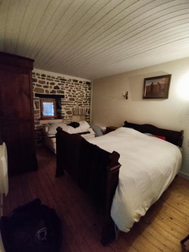 a bedroom with two beds and a stone wall at Les Gites de TY Dreux Monts d'arrée in Saint-Thégonnec