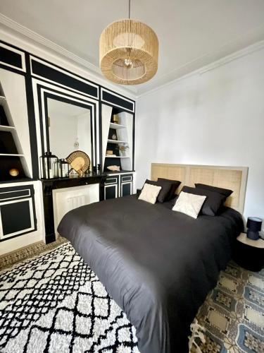 - une chambre avec un grand lit noir et un lustre dans l'établissement L'Art appart' - T2 - Lit King Size - Proche centre, à Amiens