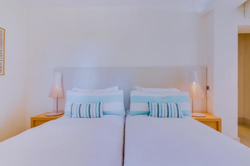 a bedroom with two beds with blue pillows at Pine Cliffs Village in Albufeira
