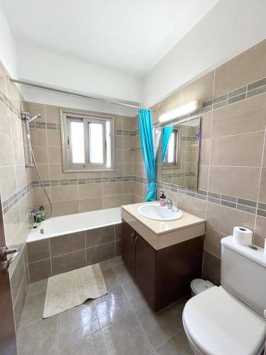 a bathroom with a sink and a tub and a toilet at SUN JULZ Apartments on the Beach in Paphos