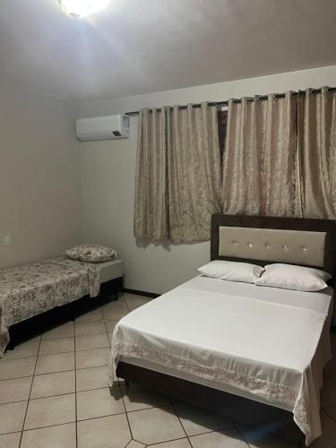 1 dormitorio con cama blanca y ventana en Pousada cravo & canela en Maringá