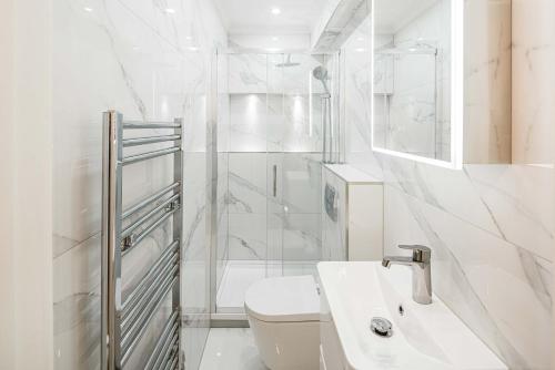 La salle de bains blanche est pourvue d'une douche et de toilettes. dans l'établissement Roof Haven at Kensington Mews, à Londres