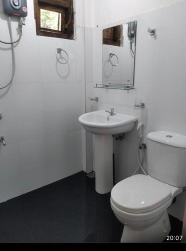 a white bathroom with a toilet and a sink at King's Lodge in Nuwara Eliya