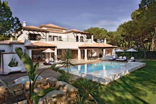 een huis met een zwembad in een tuin bij Pine Cliffs Village in Albufeira