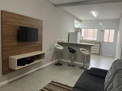 sala de estar con TV de pantalla plana en la pared en Apartamento Fátima PARA FAMÍLIA, en Balneário Camboriú