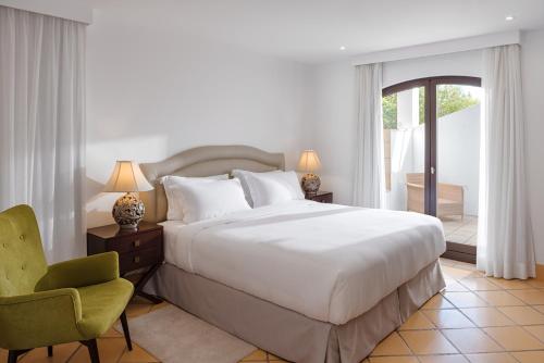 a bedroom with a large white bed and a chair at Pine Cliffs Village in Albufeira