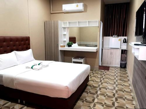 a bedroom with a large white bed and a kitchen at Banpong Center Place in Ban Khung Phayom