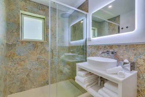 a bathroom with a sink and a glass shower at Pine Cliffs Village in Albufeira