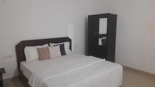 Schlafzimmer mit einem großen weißen Bett und einem Spiegel in der Unterkunft INAS Guest House in Canacona