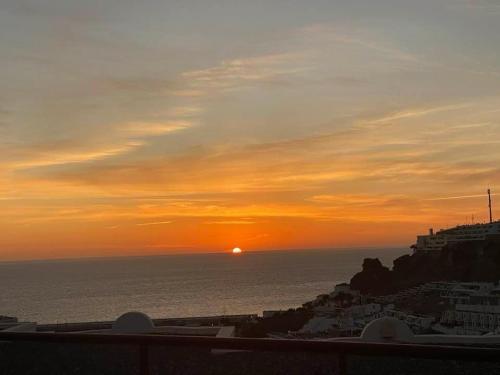 una puesta de sol sobre el océano con el sol en la distancia en Apartments Rachel Paradise, en Puerto Rico de Gran Canaria