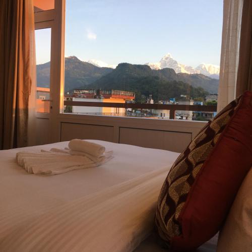 a bedroom with a bed and a window with mountains at Hotel Sheron Lilyland in Pokhara