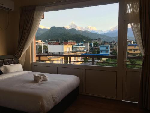 a bedroom with a bed and a large window at Hotel Sheron Lilyland in Pokhara