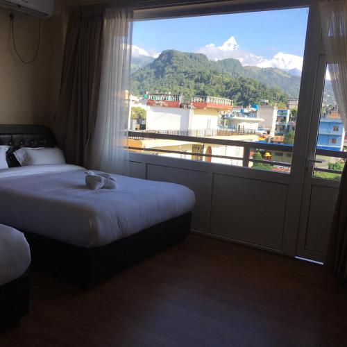 una camera d'albergo con due letti e una grande finestra di Hotel Sheron Lilyland a Pokhara