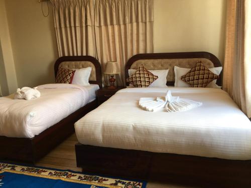 two beds in a hotel room with towels on them at Hotel Sheron Lilyland in Pokhara
