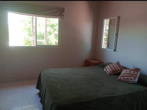 um quarto com uma cama verde e 2 janelas em El Sauce em Albardón