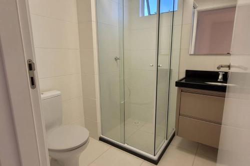 ein Bad mit einem WC und einer Glasdusche in der Unterkunft Comfort Club Santorini Centro in Piçarras