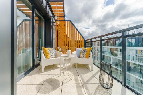 un balcón con 2 sillas y una mesa en un edificio en Bel Mare Holiday Apartments near the Beach with PARKING by Renters, en Międzyzdroje