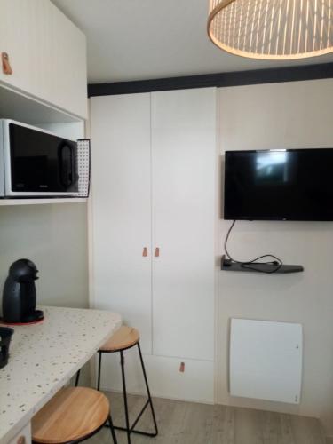 une cuisine avec des armoires blanches et une table avec des tabourets dans l'établissement La Baule Beach Box, petite studette bord de mer, à La Baule