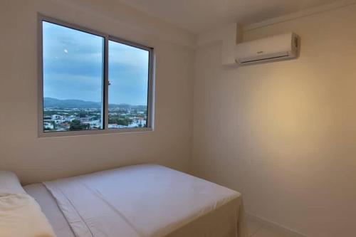 ein weißes Zimmer mit einem Bett und einem Fenster in der Unterkunft Comfort Club Santorini Centro in Piçarras