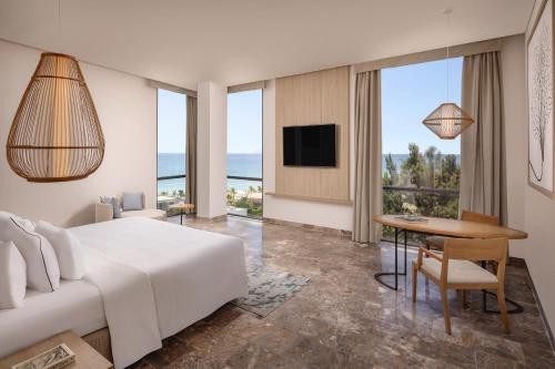 ダナンにあるMelia Danang Beach Resortのベッド、テーブル、テレビが備わるホテルルームです。