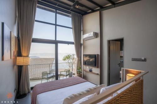 - une chambre avec un lit et un balcon avec vue dans l'établissement Zostel Plus Panchgani, à Panchgani