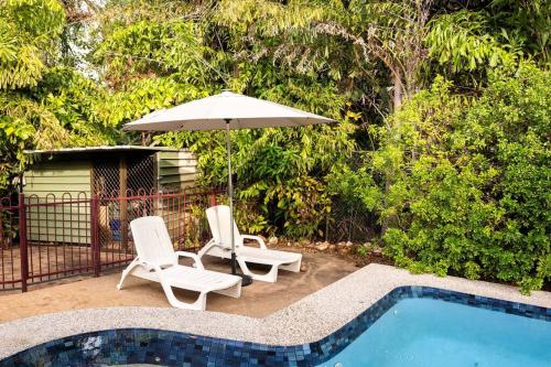 two chairs and an umbrella next to a swimming pool at Tropica Bliss: 2.5km to CBD in Stuart Park