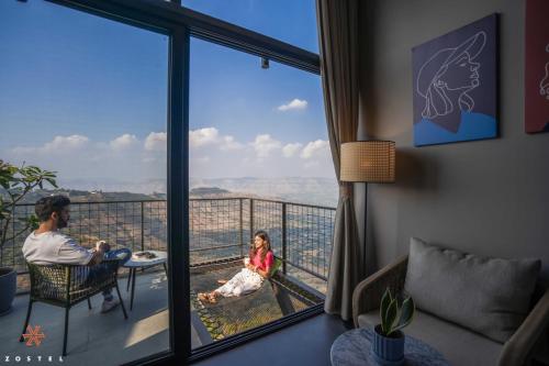 a man and a little girl sitting on a balcony in a hotel room at Zostel Plus Panchgani in Panchgani