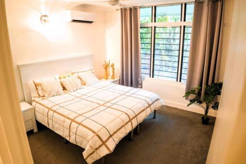 a bedroom with a bed with a large window at Tropica Bliss: 2.5km to CBD in Stuart Park