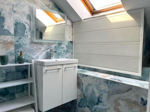 een badkamer met een witte wastafel en een dakraam bij Le Nouvo : bel appartement entièrement rénové in Corbeil-Essonnes